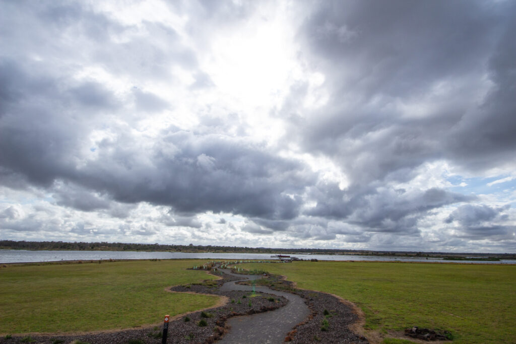 What is Budj Bim? View from the Budj Bim visitors centre over Tae Rak. The domed shape of Budj Bim can just be seen on the horizon. The path to the lake emulates the lava flow that poured south off the coastline.  